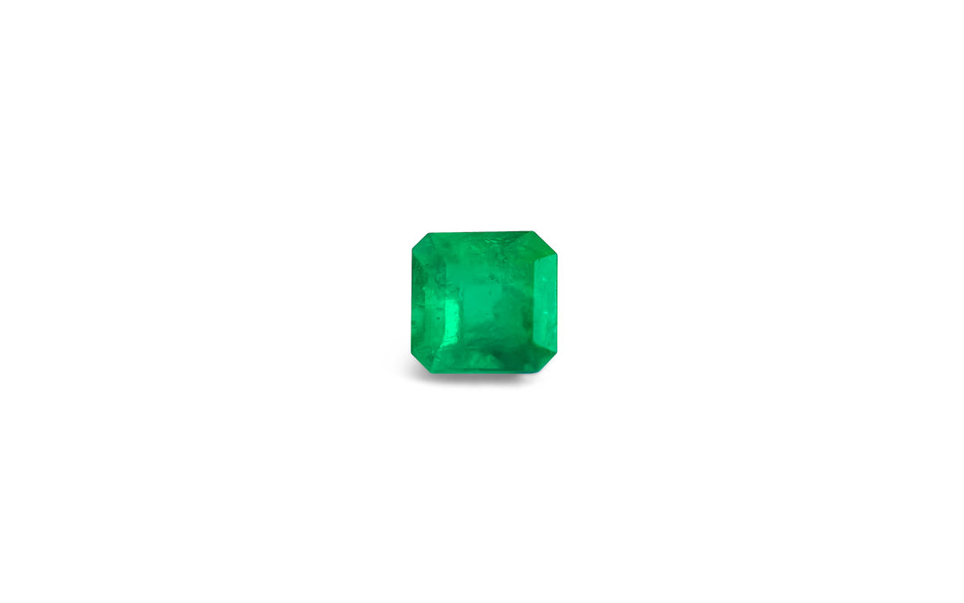 A square emerald cut green Colombian emerald gemstone is displayed on a white background.