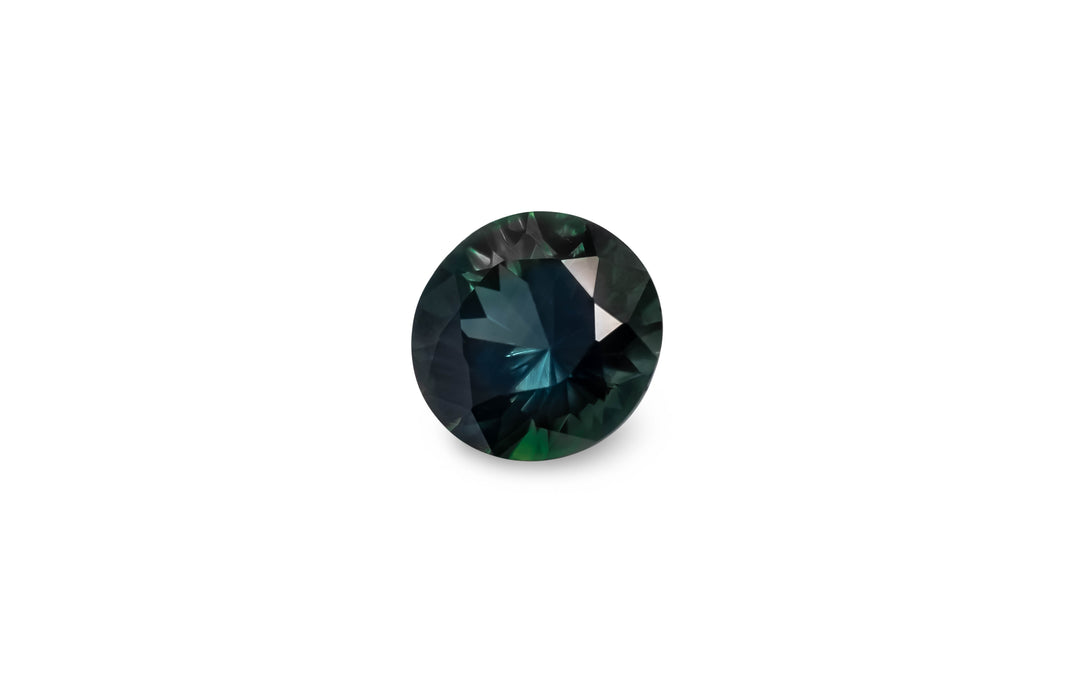 A round brilliant cut, blue/green Australian Parti sapphire gemstone is displayed on a white background.