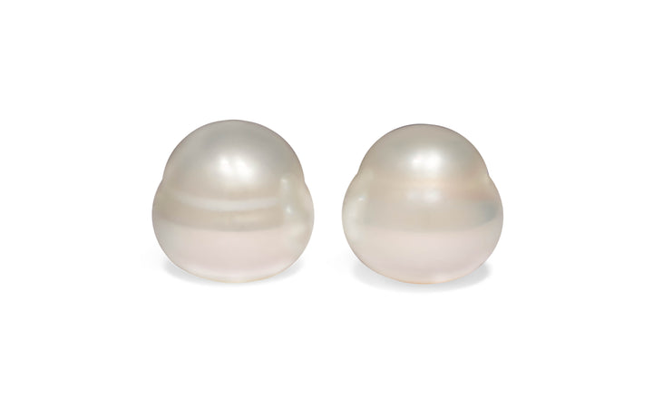 A  pair of bell white South Sea pearls are displayed on a white background.