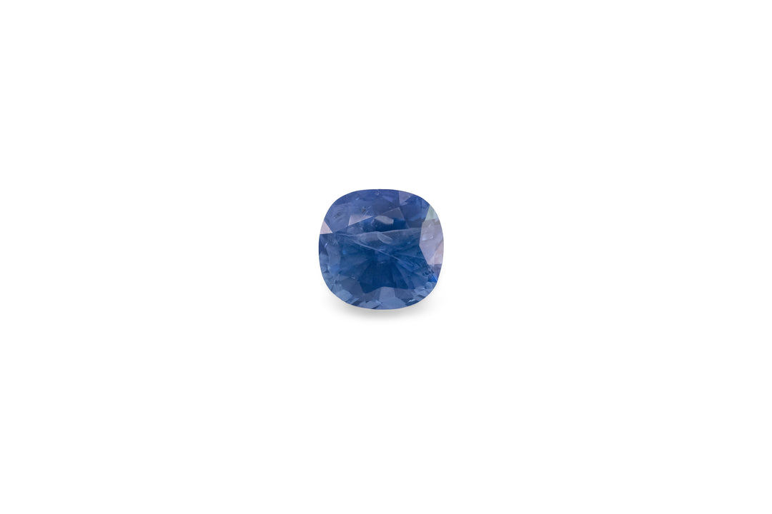 A cushion cut blue Ceylon sapphire gemstone is displayed on a white background.