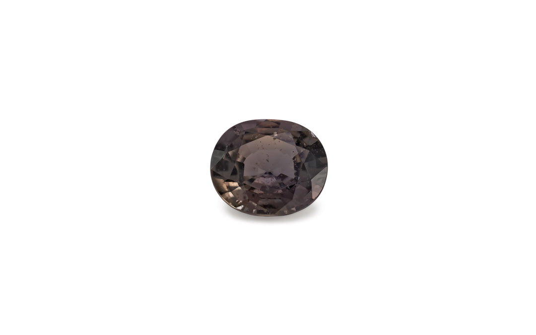 An oval cut brown sapphire gemstone is displayed on a white background.