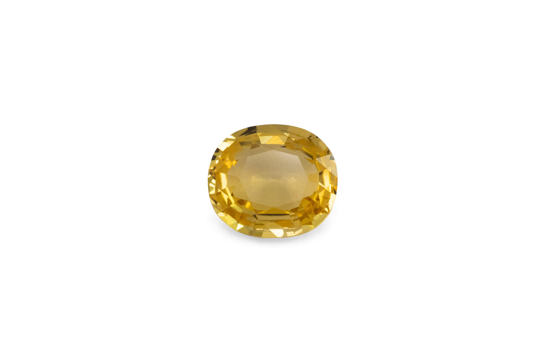 A cushion cut golden yellow sapphire is displayed on a white background.