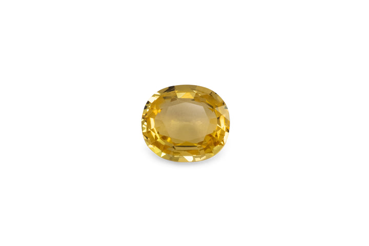 A cushion cut golden yellow sapphire is displayed on a white background.