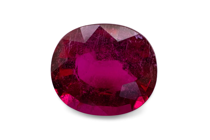 A cushion cut hot pink rubellite tourmaline is displayed on a white background.