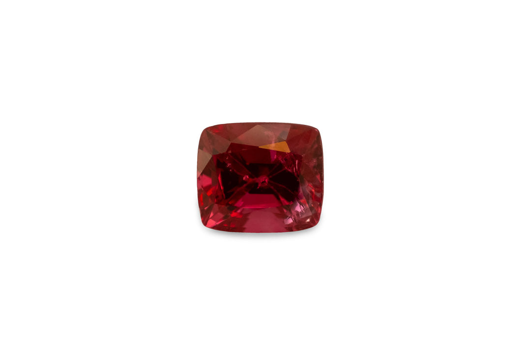 A cushion cut red Burmese spinel gemstone is displayed on a white background.