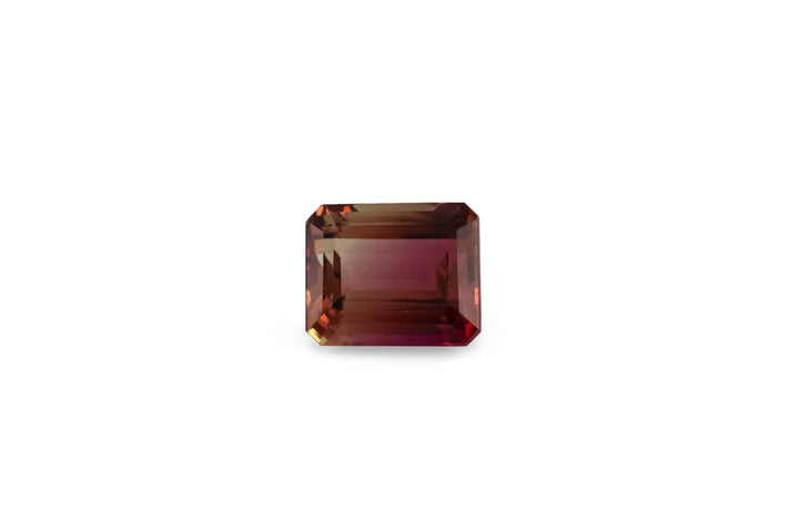 An emerald cut bi-colour deep pink and yellow tourmaline is displayed on a white background. 