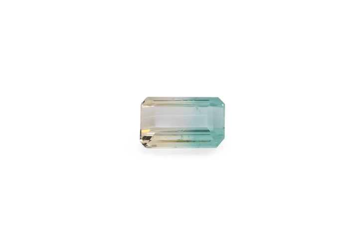 An emerald cut pale green and yellow tourmaline gemstone is displayed on a white background.