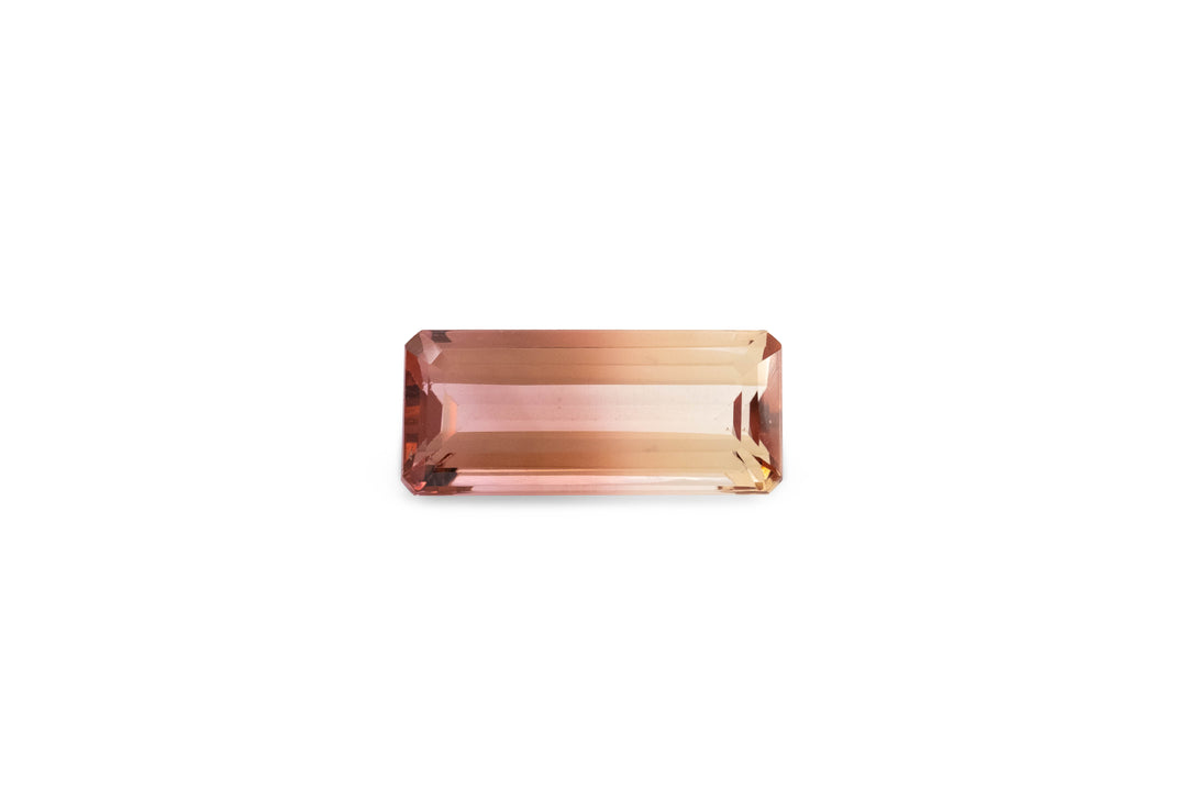 An emerald cut bi-colour pink and yellow tourmaline gemstone is displayed on a white background.