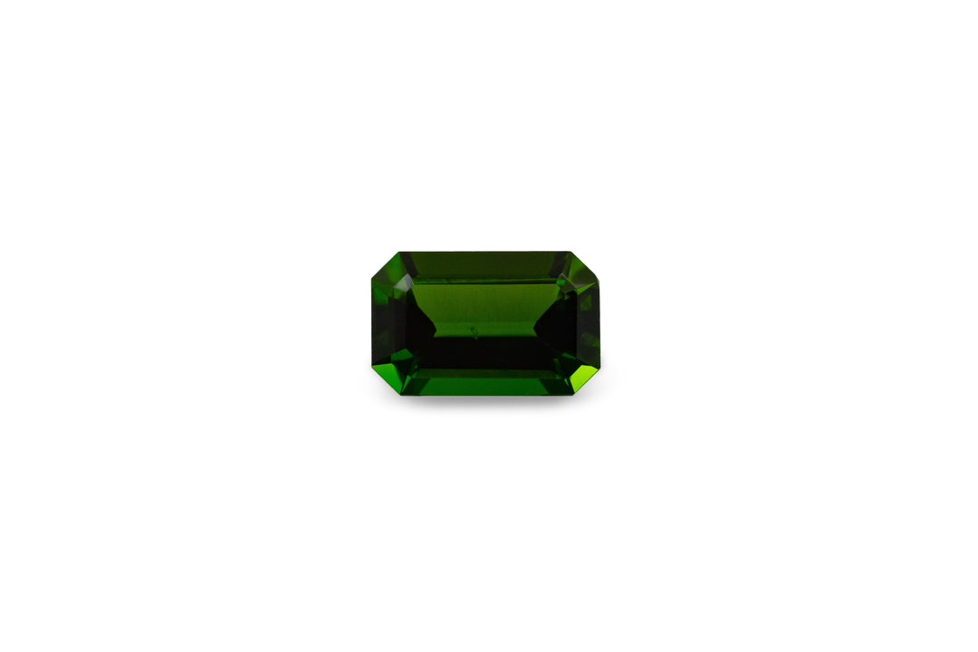 An emerald cut chrome tourmaline is displayed on a white background.
