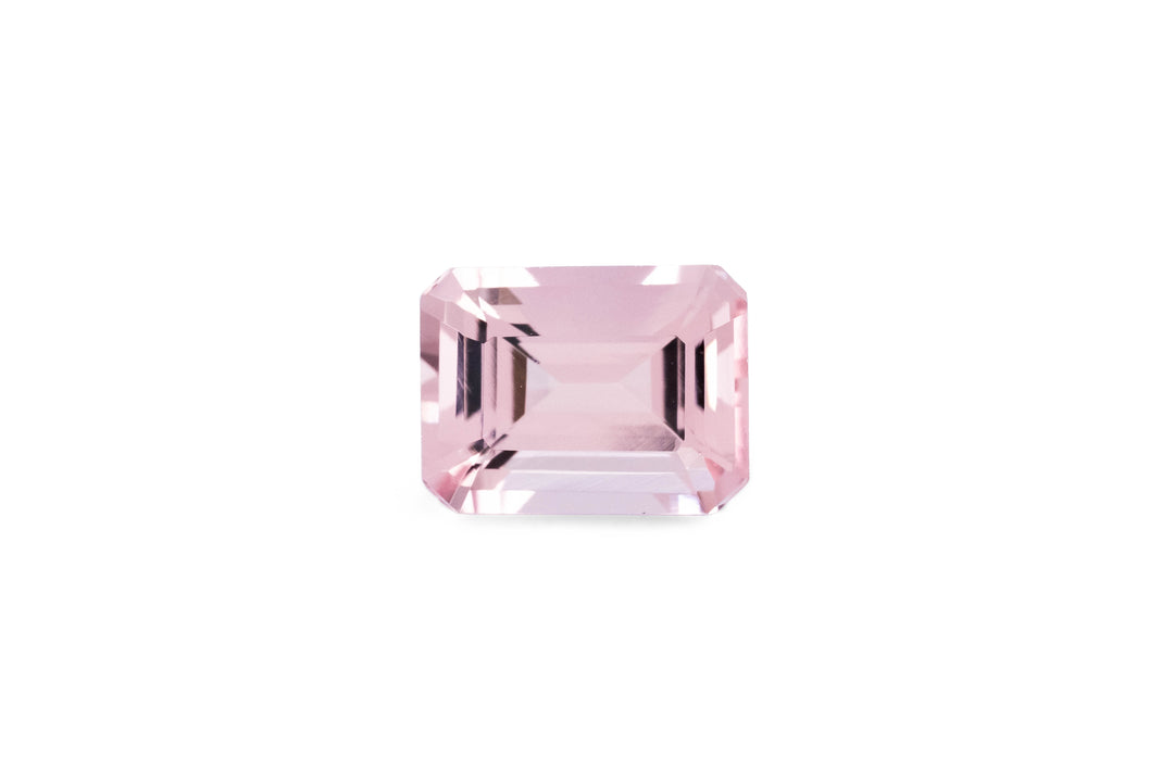 An emerald cut pink morganite gemstone is displayed on a white background.