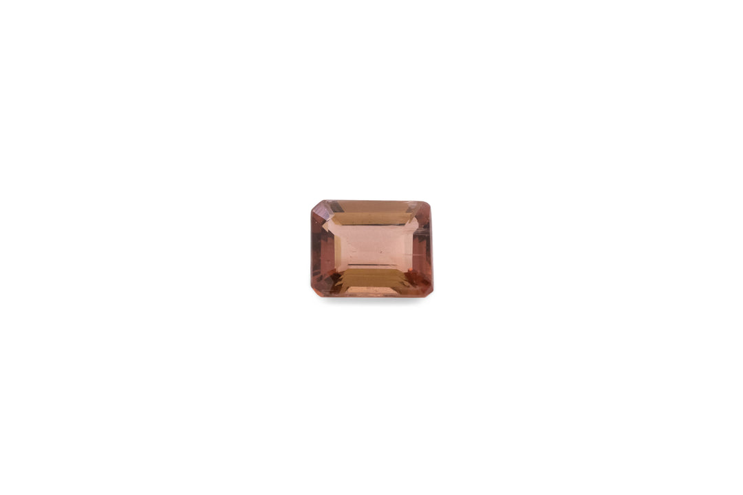 An emerald cut pink tourmaline gemstone is displayed on a white background.