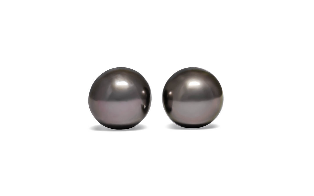 A pair of semi-round aubergine Tahitian pearls are displayed on a white background.