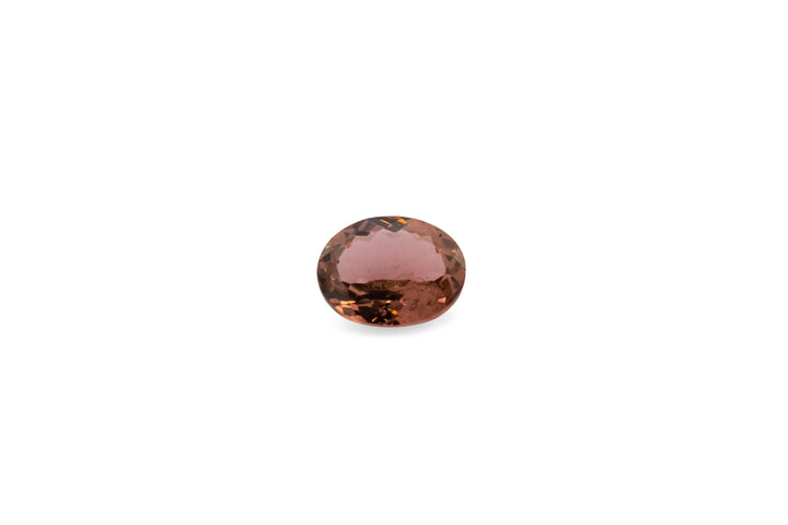An oval cut pink tourmaline gemstone is displayed on a white background.