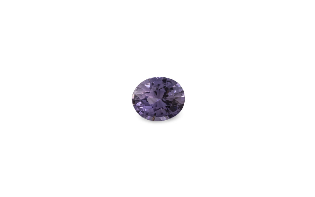 An oval cut purple Ceylon sapphire gemstone is displayed on a white background.