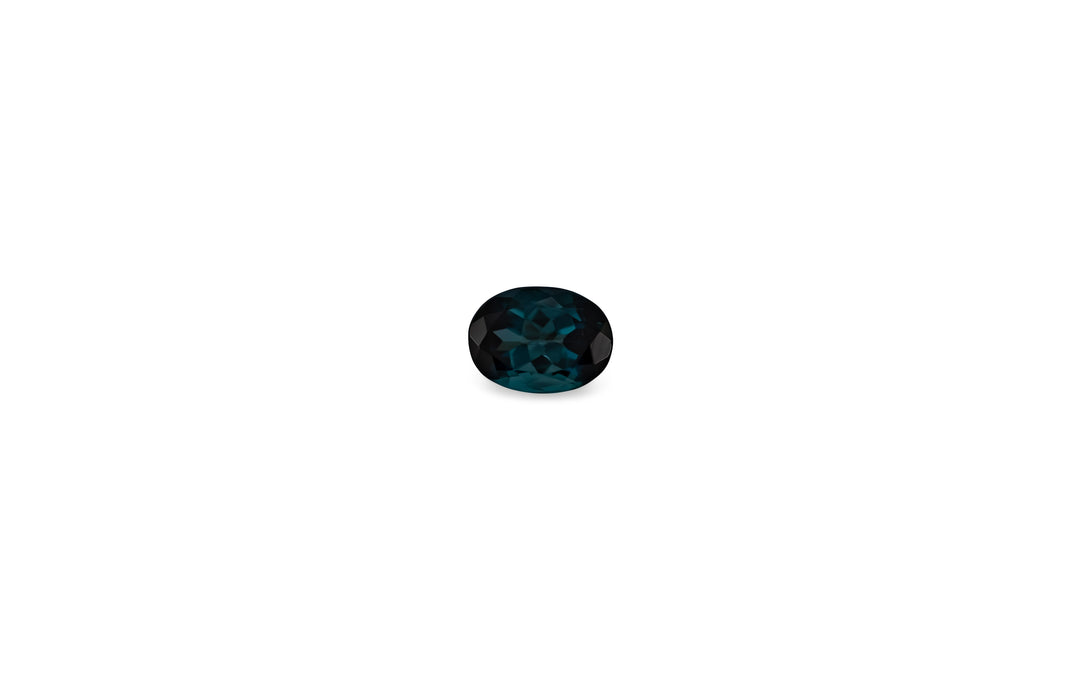 An oval cut, teal coloured sapphire gemstone is displayed on a white bcakground.