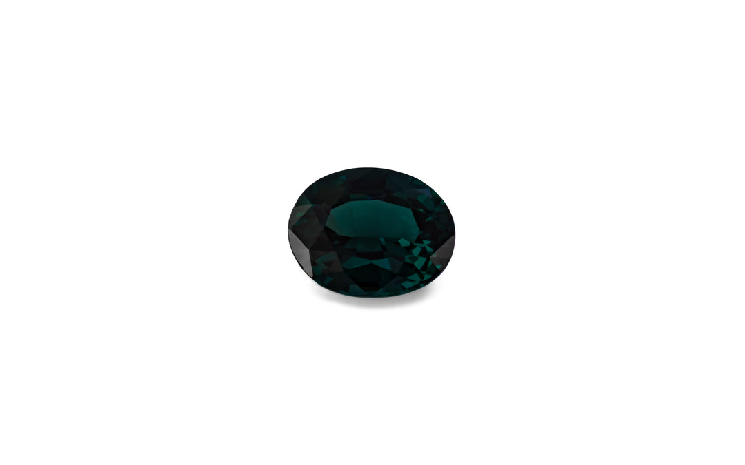 An oval cut teal spinel gemstone is displayed on a white background.