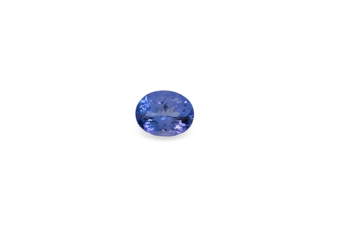 An oval cut blue Tanzanite gemstone is displayed on a white background.