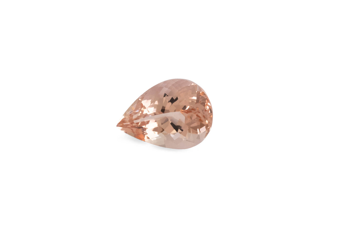 A pear cut peach coloured morganite gemstone is displayed on a white background.