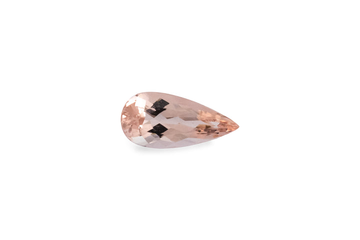 A pear cut pale peach morganite gemstone is displayed on a white background.