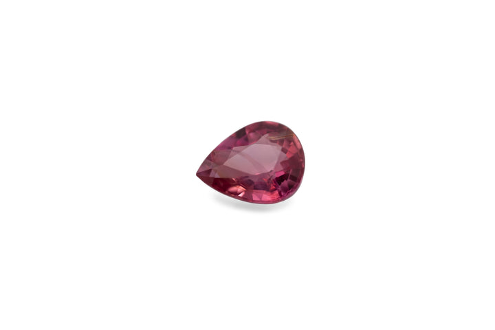 A pink pear cut Sapphire gemstone is displayed on a white background.