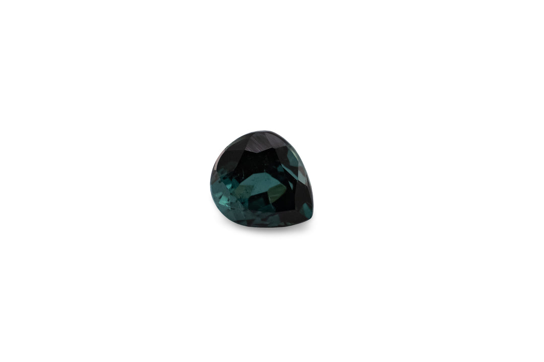 A pear cut teal tourmaline is displayed on a white background.