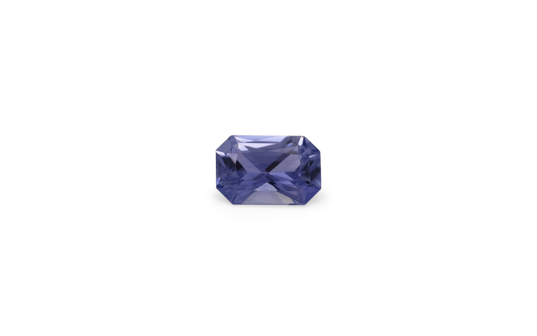 A radiant cut purple Ceylon Sapphire gemstone is displayed on a white background. 