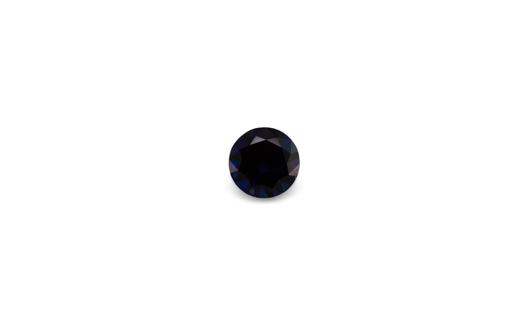A round brilliant cut, deep blue Australian sapphire is displayed on a white background.