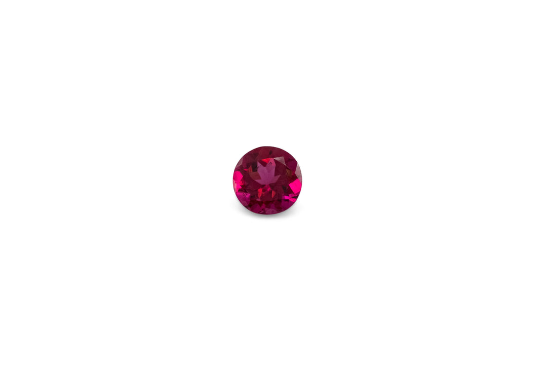 A round brilliant cut hot pink rubellite tourmaline is displayed on a white background.
