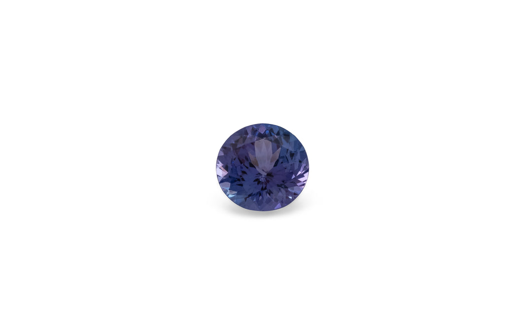 A round brilliant cut purple/blue tanzanite gemstone is displayed on a white background.