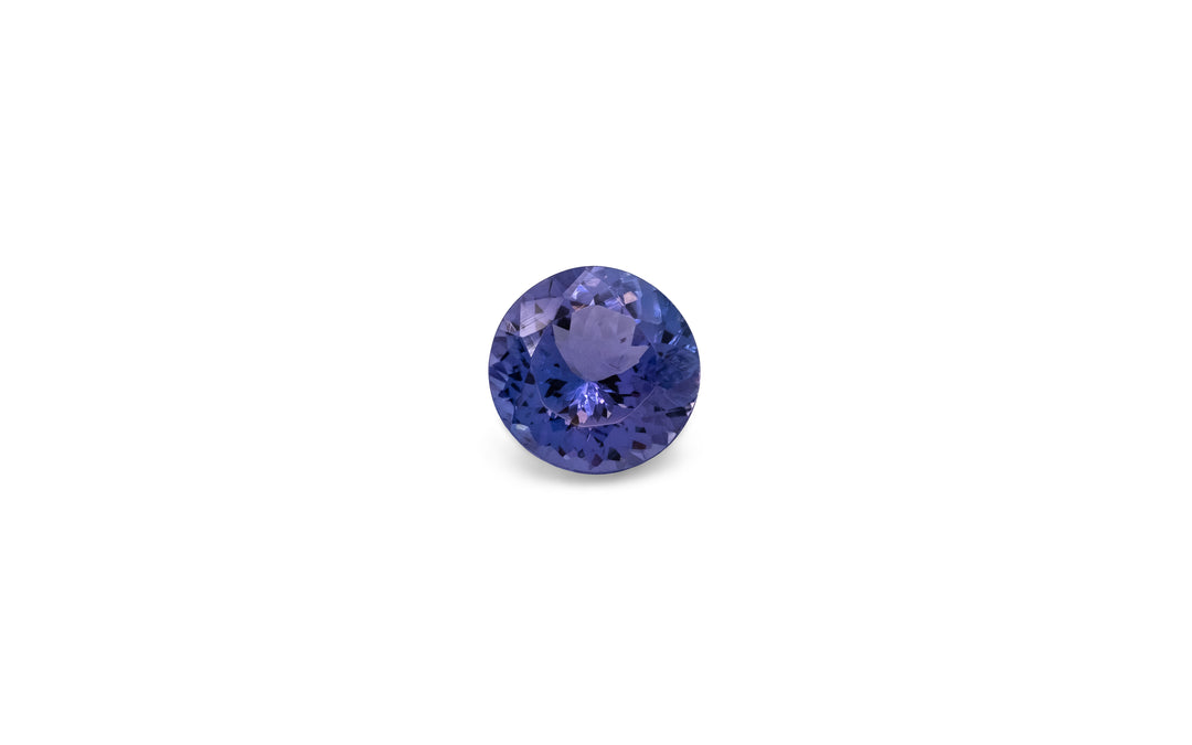 A round brilliant purple/blue tanzanite gemstone is displayed on a white background.