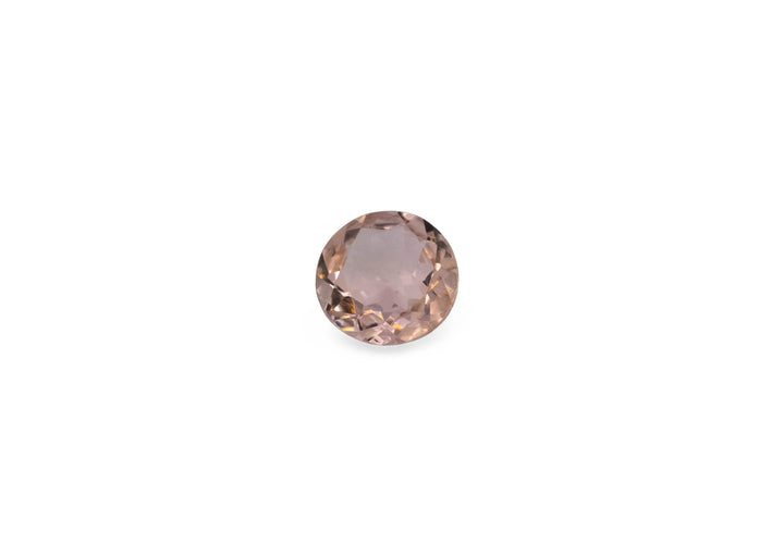 A round cut pale pink tourmaline is displayed on a white background.