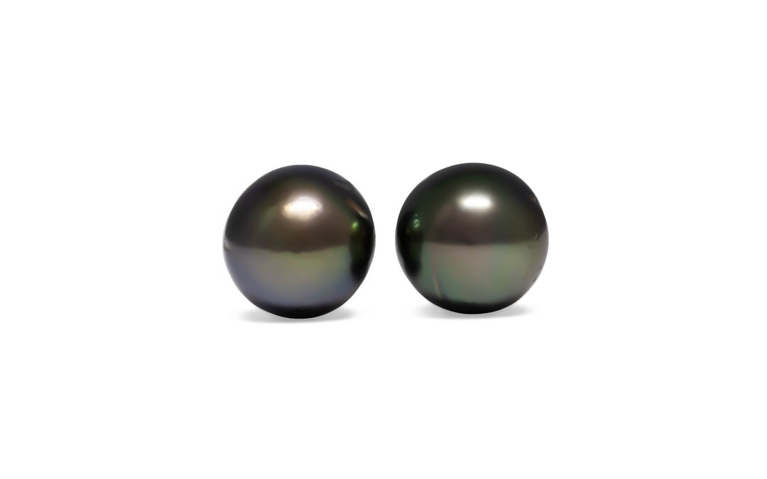A pair of round aubergine/green Tahitian pearls are displayed on a white background.
