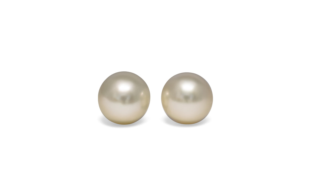 A pair of semi round, cream, white south sea pearls are displayed on a white background.