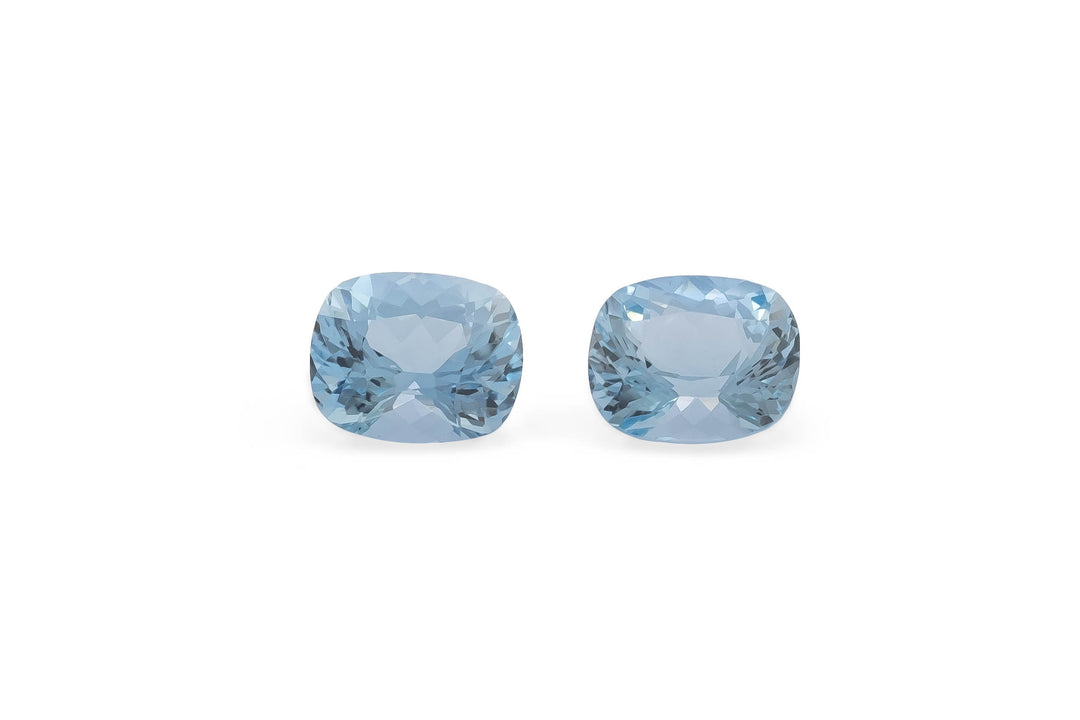 A pair of cushion cut pale blue Madagascan Aquamarine gemstones on a white background.
