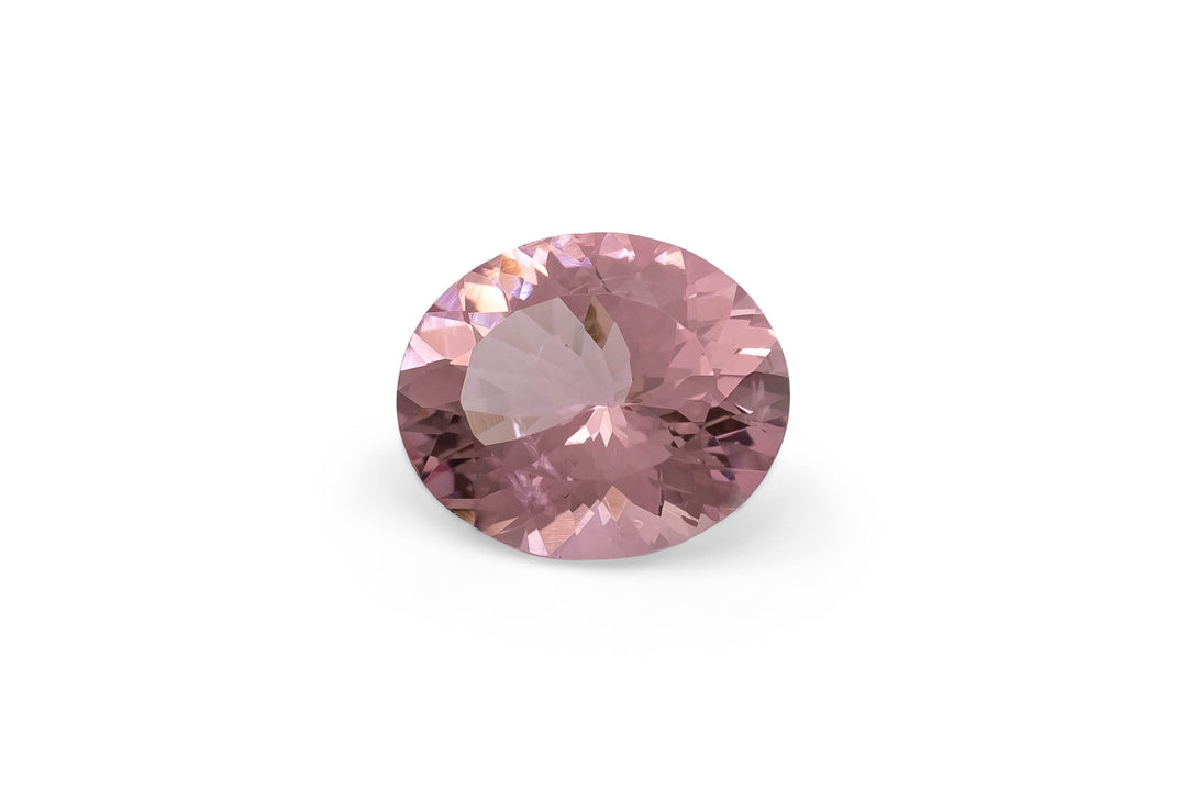 Oval cut pink morganite gemstone on a white background.