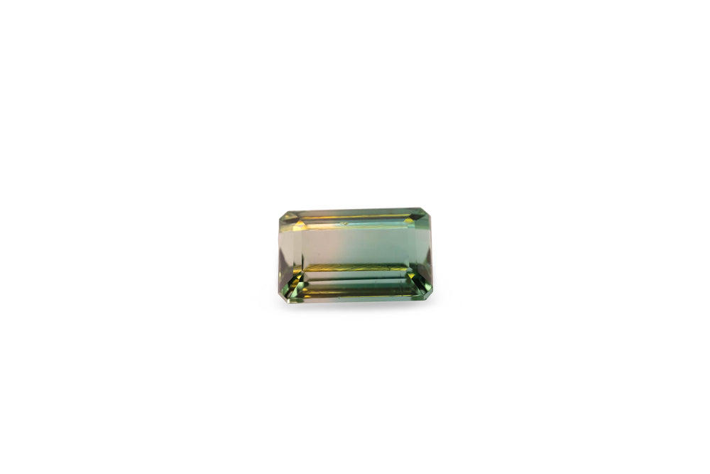 An emerald cut bi-colour green tourmaline gemstone is displayed on a white background.