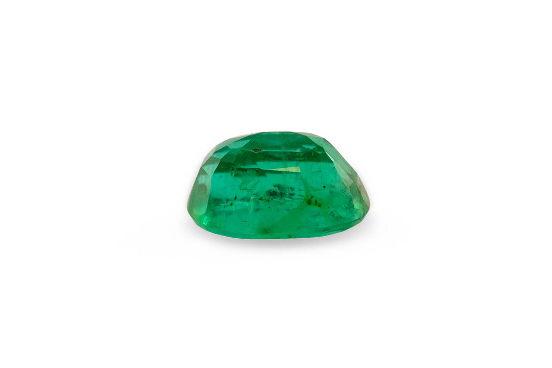 An oval cut Brazilian green emerald gemstone is displayed on a white background.
