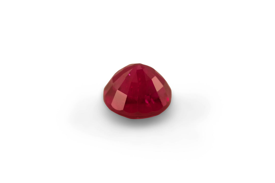 A round brilliant cut Burmese ruby gemstone is displayed on a white background.