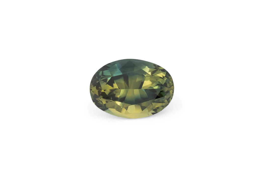 Oval cut tri-colour Australian parti sapphire gemstone featuring zones of yellow and green with a hint of teal on a plain white background.