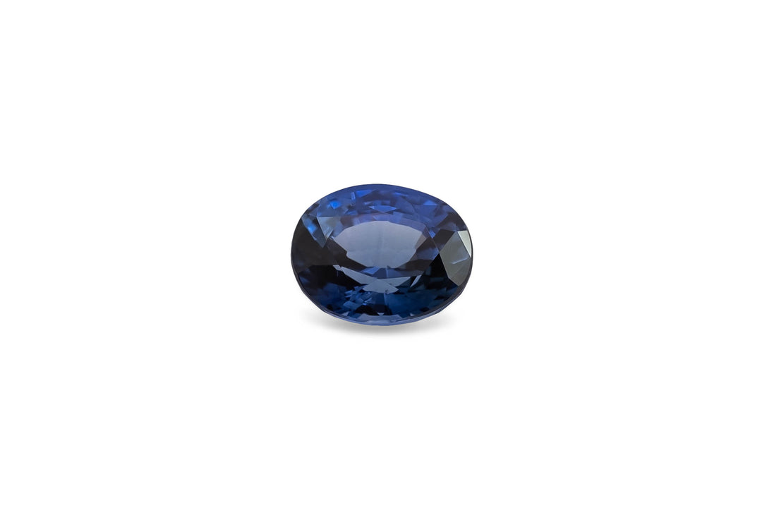 Oval cut deep blue Ceylon sapphire gemstone on white background.