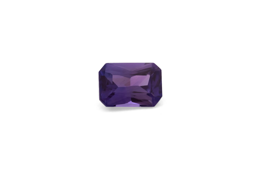 Radiant cut purple Ceylon sapphire gemstone on a white background.